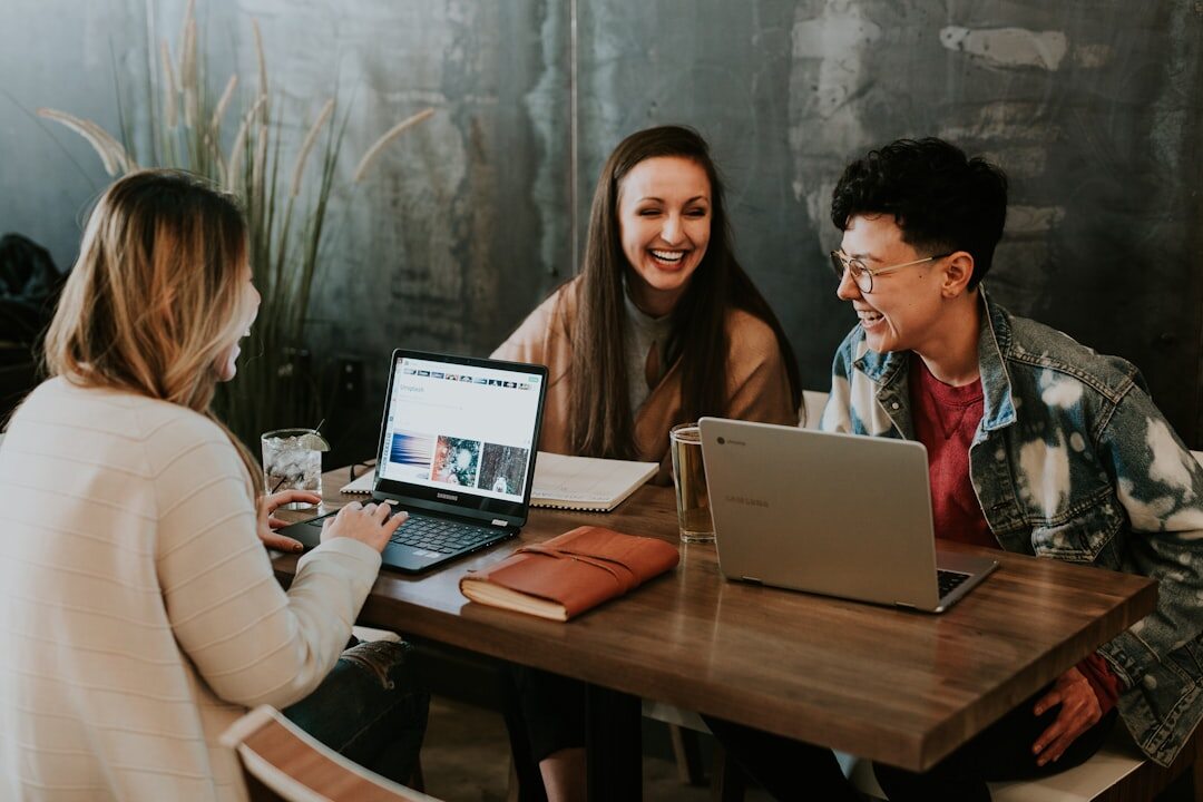 Small editorial team collaborating around a laptop in a bright office